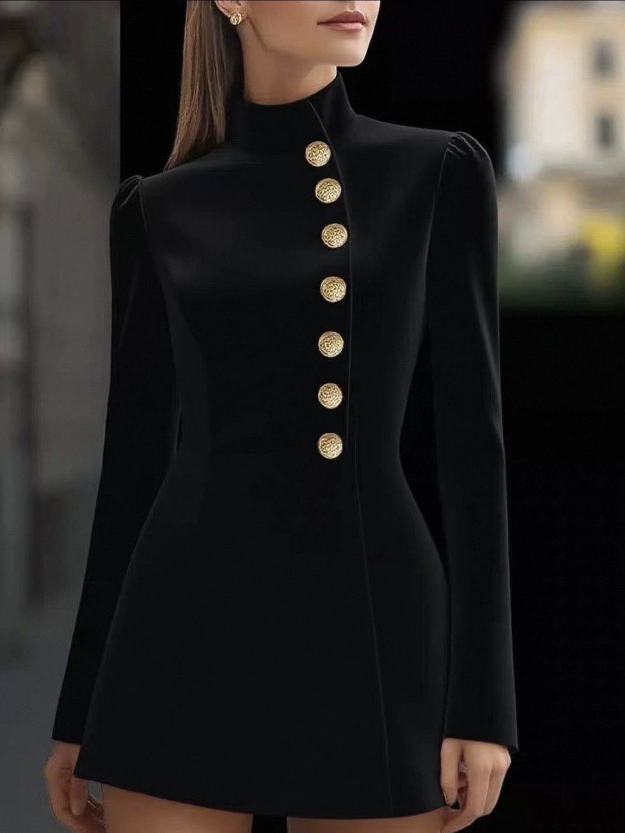 Black dress with gold buttons worn by a model against a blurred background