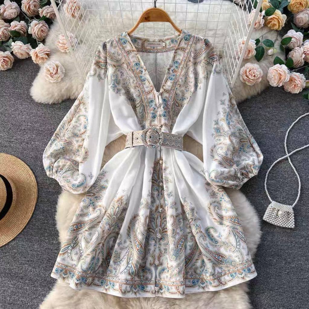 Floral dress with long sleeves on a hanger against a decorative background with flowers and a bag.