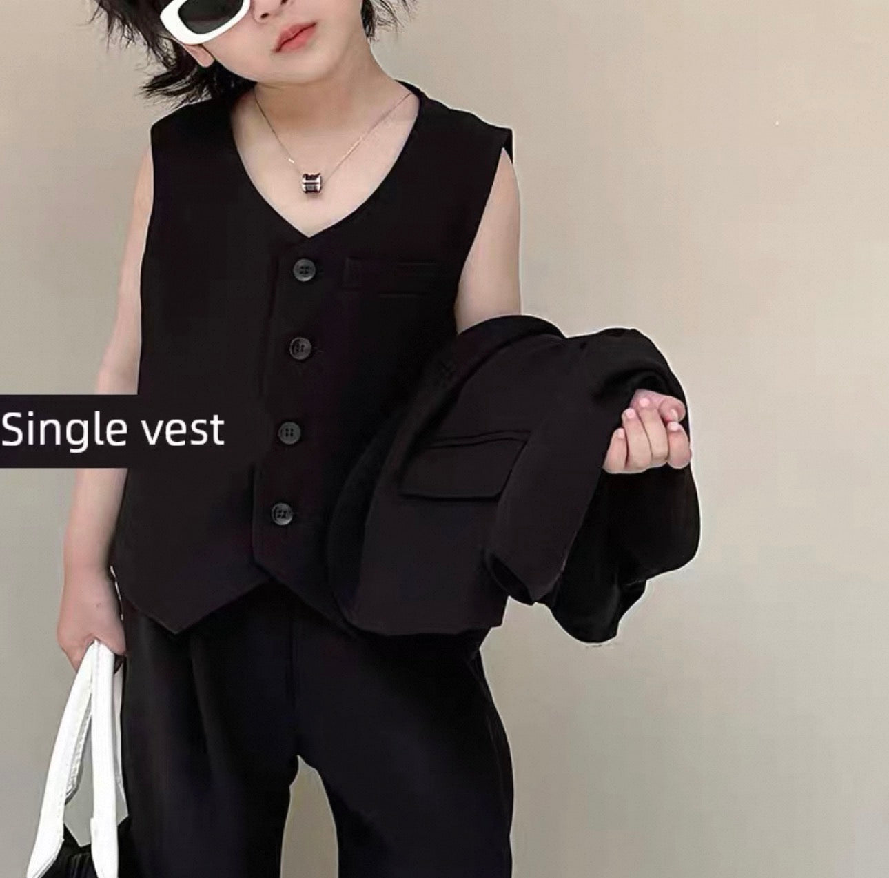 Person wearing a black vest over a black shirt with a plain background