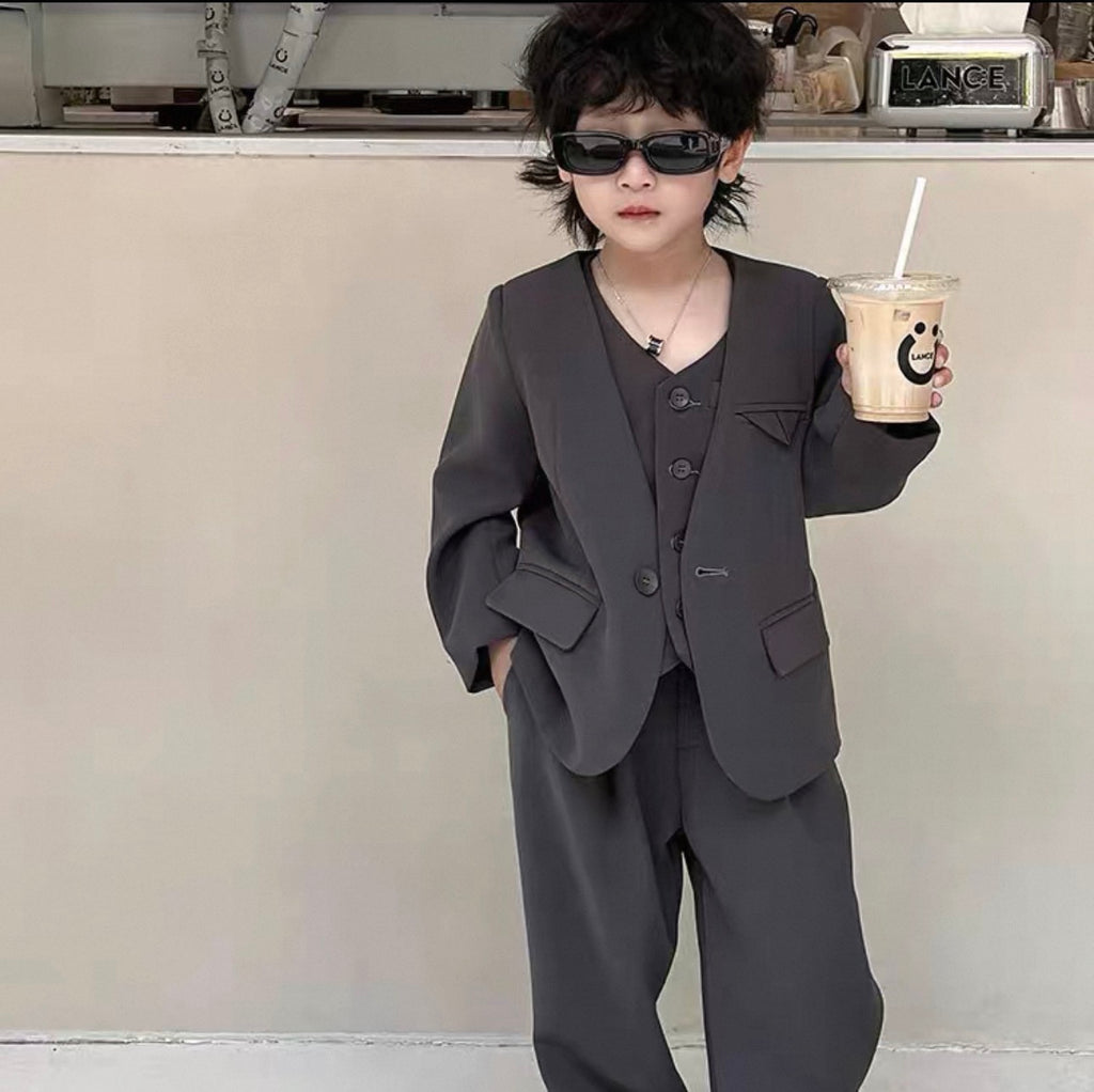 Child in a dark suit holding a drink in a kitchen setting