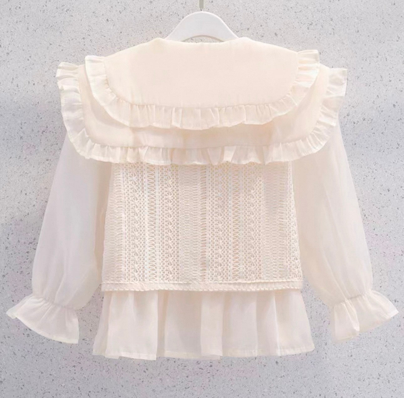 White blouse with ruffled details on a gray background