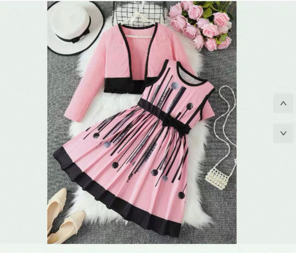 Pink and black dress with matching cardigan on a textured surface with flowers and shoes.
