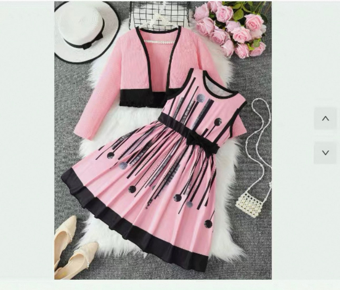 Pink and black dress with matching cardigan on a textured surface with flowers and shoes.
