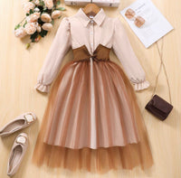 Two-tone dress with beige top and brown skirt on a wooden surface with shoes and flowers.