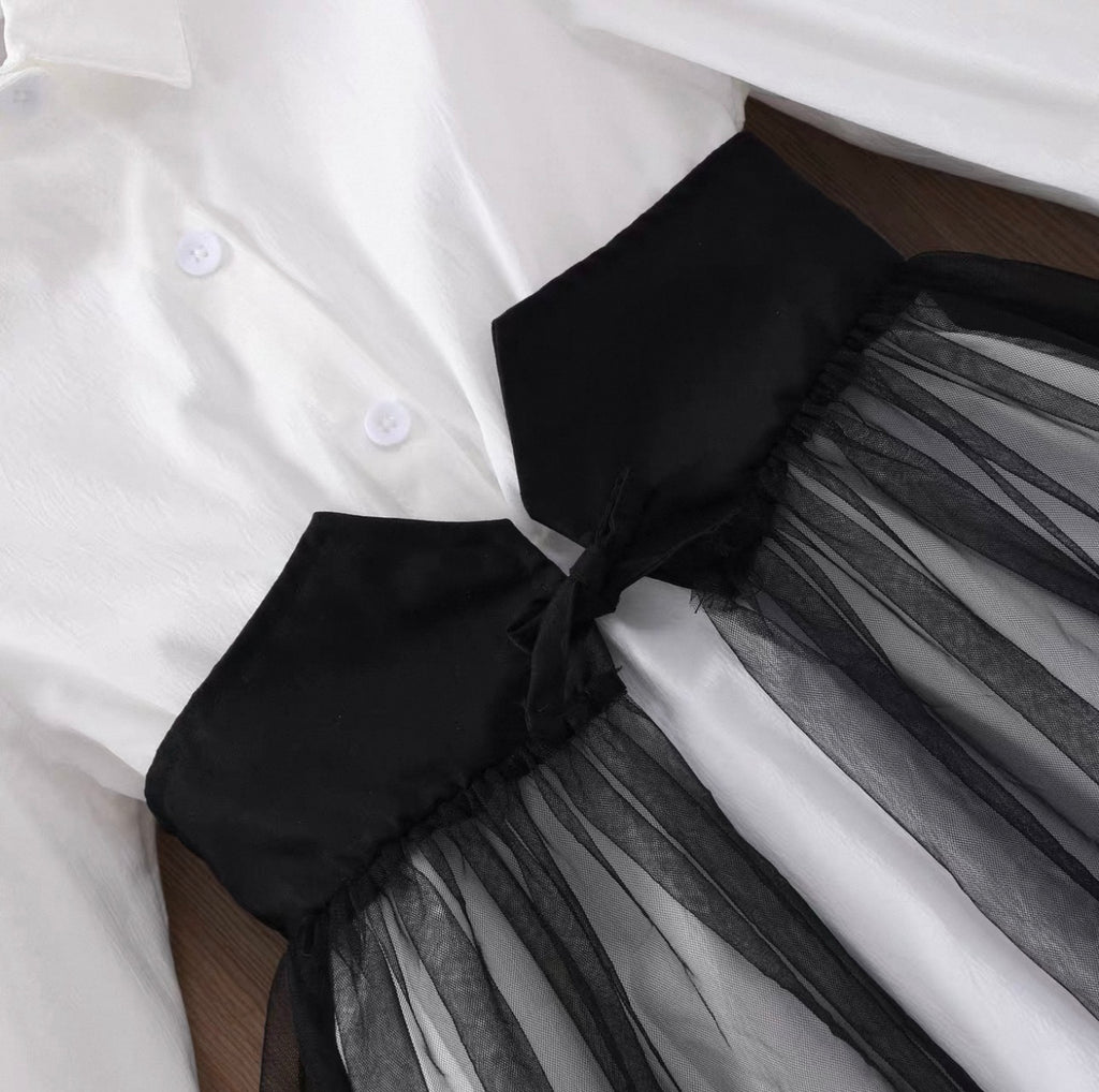 Close-up of a white shirt with a black bow and sheer black skirt.