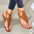 Brown sandals worn with rolled-up jeans on a neutral background