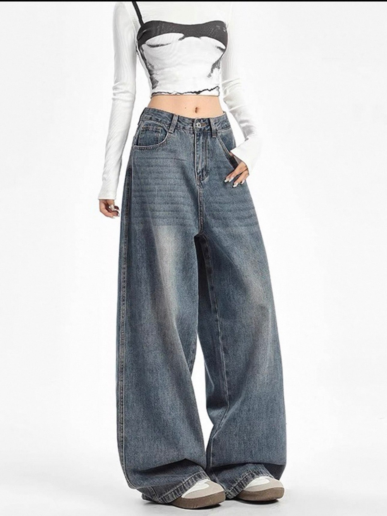 Person wearing a white long-sleeve crop top, black and white patterned crop top, and wide-leg blue jeans on a white background.