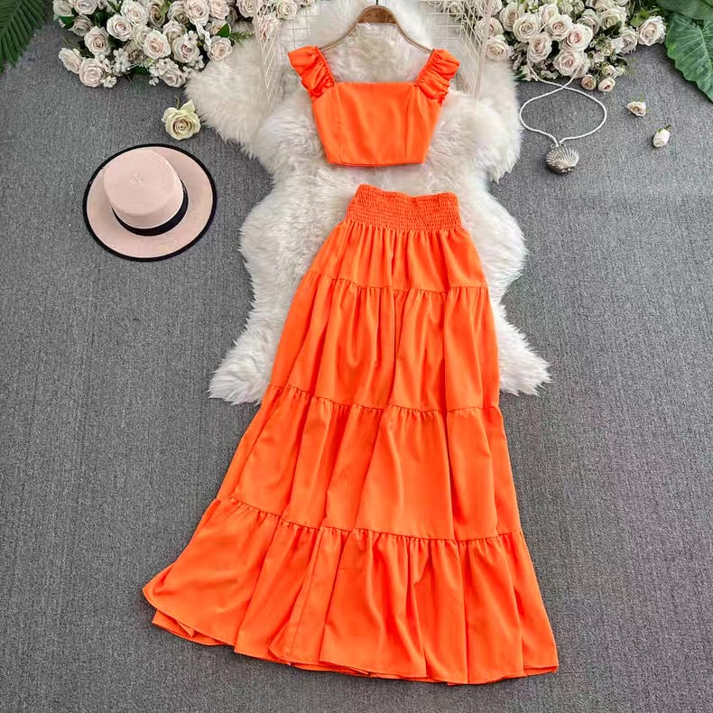 Orange dress with matching top on a textured surface with flowers and a hat.