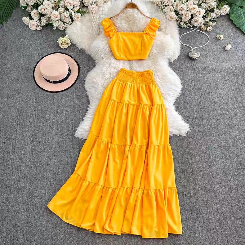 Yellow dress with top and skirt on a gray surface with flowers and a hat.